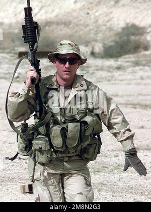 A US Navy Lieutenant, a SEAL from SEAL Team 8, runs down a firing range holding a Colt 5.56mm M4 Carbine Rifle. He's in Kuwait as part of the Southwest Asia buildup. Country: Kuwait (KWT) Stock Photo