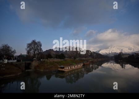 Srinagar, India. 14th Jan, 2023. View of Jhelum River and snow covered Zabarwan hills during a sunny day after fresh snowfall in Srinagar. Weather office has forecast dry weather in Kashmir till January 14-18. Credit: Pacific Press Media Production Corp./Alamy Live News Stock Photo