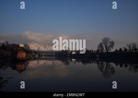 Srinagar, India. 14th Jan, 2023. View of Jhelum River and snow covered Zabarwan hills during a sunny day after fresh snowfall in Srinagar. Weather office has forecast dry weather in Kashmir till January 14-18. Credit: Pacific Press Media Production Corp./Alamy Live News Stock Photo