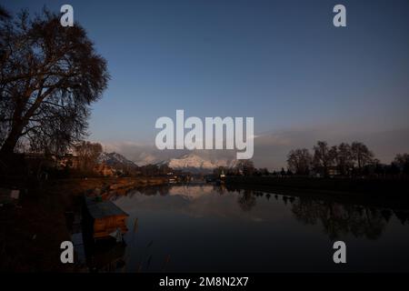 Srinagar, India. 14th Jan, 2023. View of Jhelum River and snow covered Zabarwan hills during a sunny day after fresh snowfall in Srinagar. Weather office has forecast dry weather in Kashmir till January 14-18. Credit: Pacific Press Media Production Corp./Alamy Live News Stock Photo