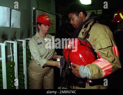 During a general quarters drill aboard the auxiliary command ship USS CORONADO (AGF 11), Machinist Mate CHIEF (SW) Laurie Mecham (left) hands out OBA cannisters to fire party members as they prepare to fight a simulated fire during RIMPAC 98. Subject Operation/Series: RIMPAC '98 Country: Pacific Ocean (POC) Stock Photo