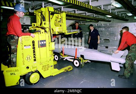 US Navy Aviation Ordnancemen from the Weapons Department aboard USS ENTERPRISE (CVN 65) position a recently received JSOW (AGM-154) weapon onto a skid for transport to the flight deck. Enterprise is forward deployed, operating in the Mediterranean. Base: USS Enterprise (CVN 65) Stock Photo