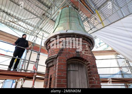 Rostock, Germany. 03rd Jan, 2023. Nils Sommer, project manager in charge of the municipal property management and development company of the city of Rostock (KOE), is standing on the roof of the water tower under a building tarpaulin next to the last remaining of the seven copper-covered turrets. The other six were dismantled for refurbishment. Renovation of the water tower, built in 1903, had begun in May 2018 and is scheduled to be completed in 2024, according to current plans. The tower, which is more than 40 meters high, has long had problems with moistu Credit: dpa/Alamy Live News Stock Photo