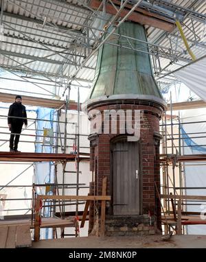 Rostock, Germany. 03rd Jan, 2023. Nils Sommer, project manager in charge of the municipal property management and development company of the city of Rostock (KOE), is standing on the roof of the water tower under a building tarpaulin next to the last remaining of the seven copper-covered turrets. The other six were dismantled for refurbishment. Renovation of the water tower, built in 1903, had begun in May 2018 and is scheduled to be completed in 2024, according to current plans. The tower, which is more than 40 meters high, has long had problems with moistu Credit: dpa/Alamy Live News Stock Photo