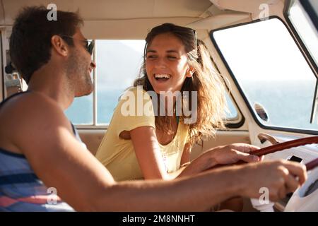 Feeling free in good company. Young happy couple having fun while driving their mini van across the country. Stock Photo