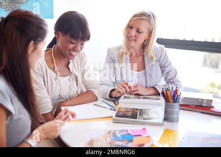 Coming up with new designs. three businesswoman gathered around a table in the office. Stock Photo