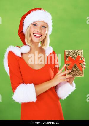 A golden gift that will make one glow. Attractive woman in a Christmas costume holding up a gift wrapped in golden paper. Stock Photo