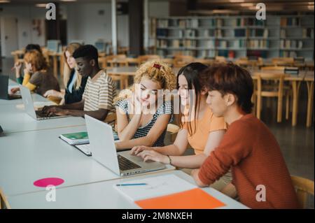 Multiracial young students using netbooks in library Stock Photo