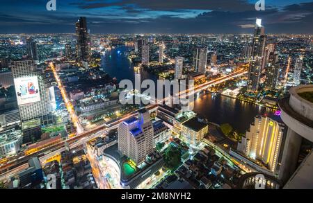 Scenic high rooftop view,taken at dusk,just after sunset,looking west.Light trails of river boats and traffic over bridges and fly-overs.Afterglow in Stock Photo