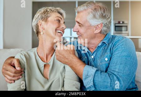 A happy relaxed mature retired couple talking and laughing together in the living room. Smiling caucasian couple bonding on the sofa at home Stock Photo