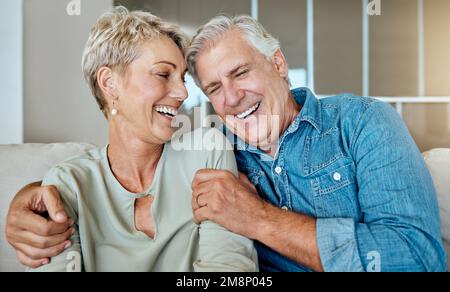 A happy relaxed mature retired couple talking and laughing together in the living room. Smiling caucasian couple bonding on the sofa at home Stock Photo