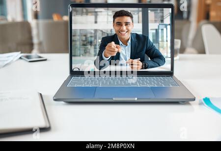 Happy mixed race businessman pointing his finger on a video call using a laptop alone at work. One hispanic businessperson smiling on a virtual call Stock Photo