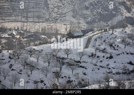 Srinagar, India. 14th Jan, 2023. Residents walk through a snow covered road after a fresh snowfall on the outskirts of Srinagar. Weather improved in Kashmir valley after days of moderate to heavy snowfall and rains. Meanwhile, Avalanches were reported on Saturday in Bandipora district and Sonamarg hill station which have been witnessing moderate to heavy snowfall over past few days. This is the second incident reported in the popular hill station in the last two days. Two labourers died on Thursday when an avalanche hit the work site of a construction company in Sonamarg. Credit: SOPA Images L Stock Photo