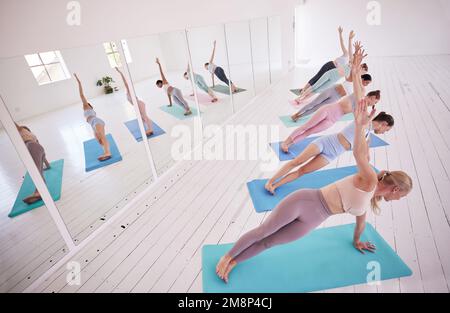 Group of women in side plank in pilates studio. Group of women doing yoga class together. Women balance their body in yoga studio. Group of women Stock Photo
