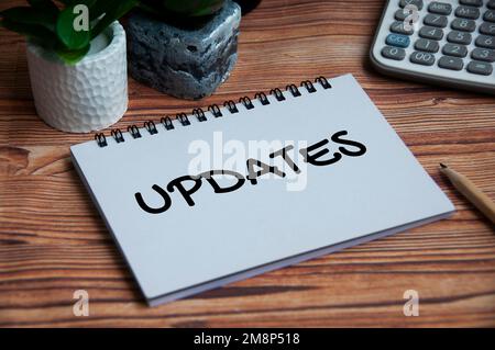 Updates text on notebook with green plant and calculator background. Business update concept. Stock Photo