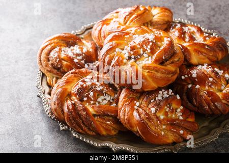 Kanelbullar or Kanelbulle is a traditional Swedish cinnamon buns flavored with cinnamon and cardamom spices and topped with pearl sugar close-up on a Stock Photo