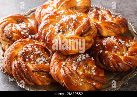 Swedish cinnamon rolls kanelbullar topped with pearl sugar close-up on a plate on the table. Horizontal Stock Photo
