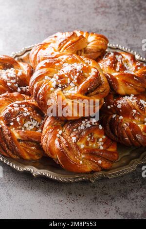 Kanelbullar Swedish cinnamon and cardamom buns with pearl sugar close-up on the plate on the table. Vertical Stock Photo