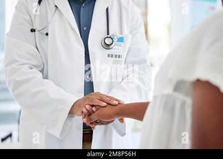 Closeup on doctor holding a patients hand. African american doctor being kind to a patient cropped. Doctor offering a patient caring support. Doctor Stock Photo