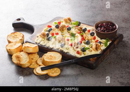 Snack Butter board topped with dried figs and cherry, fresh mint, nuts and blueberries close-up on the table. Horizontal Stock Photo