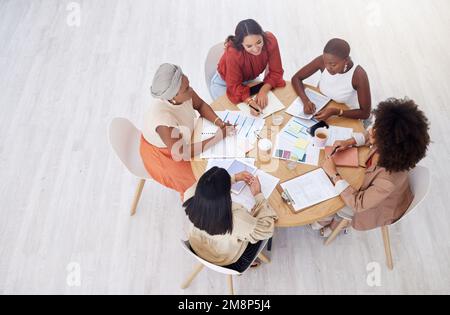 Above view of diverse group of business women having a brainstorm meeting in office with copyspace. Confident professional team sitting together and Stock Photo
