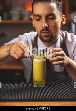 Portrait of barman adding ingredients and creating smoothie drinks on bar counter Stock Photo