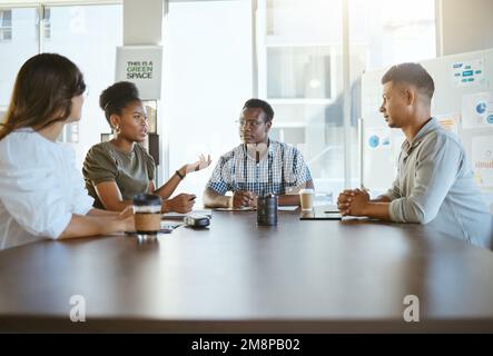 Group of diverse businesspeople having a meeting in an office at work. Happy african american businesswoman talking during a workshop at a table with Stock Photo