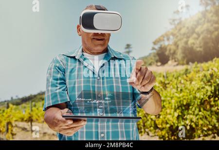 Senior mixed race farmer using virtual reality headset and digital tablet with cgi. Hispanic elderly man using technology in metaverse to browse data Stock Photo