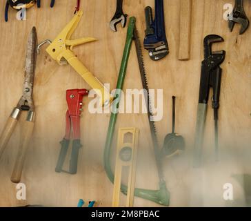 An arrangement of tools on a wooden wall. Closeup of a collection of tools hanging. Neat, tidy mechanics tools and equipment on a wall. Still life of Stock Photo