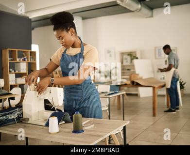 fashion designer threading needle on a sewing machine. Young tailor using sewing machine. Seamstress getting her sewing machine ready. African Stock Photo