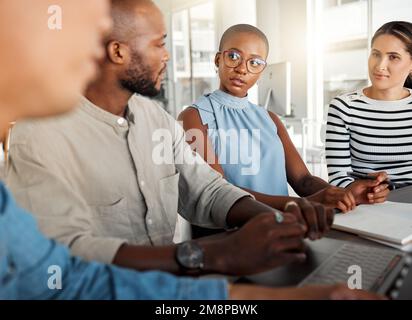 Group of diverse businesspeople having a meeting in an office at work. Business professionals talking while using a laptop together in an office Stock Photo