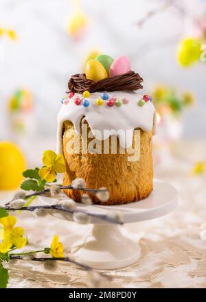 Traditional Easter Cake with chocolate nest and easter eggs candy. Easter treats with spring flowers decorations for holiday. Stock Photo