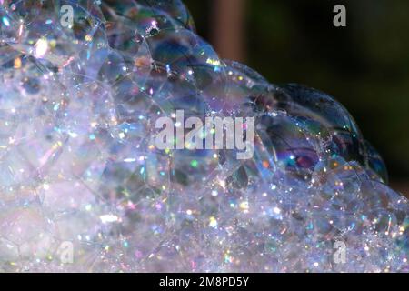 A Lot of Soap Bubbles are Bursting. Bubbles Surface on Nature Background. Texture of Big Foam. Creative concept of dreaming, happiness and magic. Abst Stock Photo