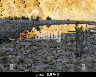 Golden Reflection of the sandstone cliffs within a calm pool in the Fish River Canyon, Namibia Stock Photo