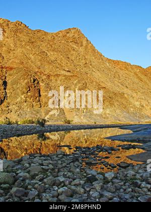 Mountain reflecting into a calm pool on a clear early morning along the Fish River Canyon, Namibia Stock Photo