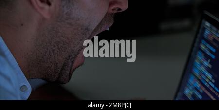 Tired programmer yawning coding and developing software Stock Photo