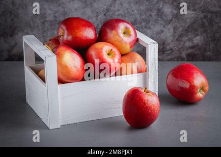 Fresh red apples in a wooden box on a grey background. Organic food Stock Photo