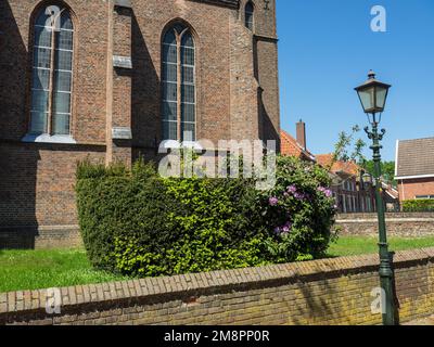 A lantern and green shrubs against an old church in Bredevoort, Netherlands on a sunny day Stock Photo