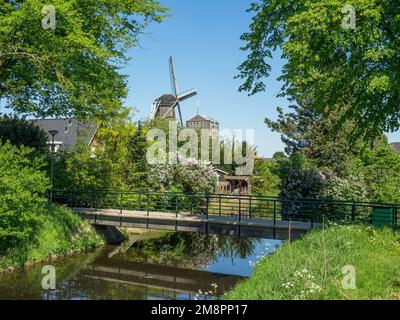 An old windmill on a bank of a river in Bredevoort, Netherlands on a sunny day Stock Photo