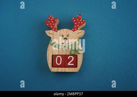 Festive wooden deer with Viva Magenta cubes 02 on blue background close-up top view. Christmas concept of date Stock Photo