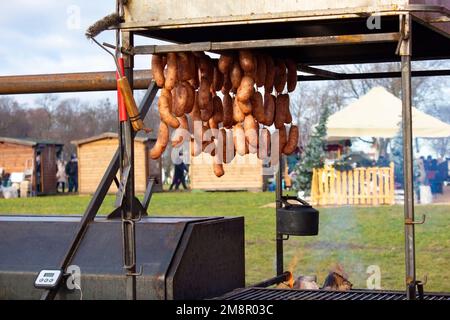 Delicious hot sausages cooked in a metal street oven hang at the food market, traditional meat products. Street Food Market. Stock Photo