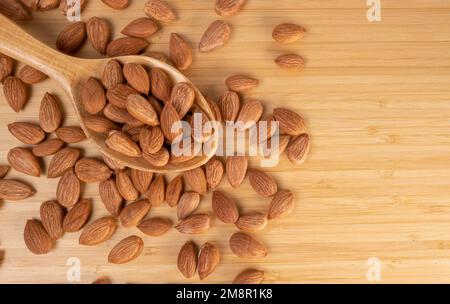 Grains Of Almond On A Wooden Floor, Top View. Almond in Wooden Spoon For Menu Concept, Copy Space. Stock Photo