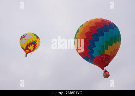 Colorful hot air balloons flying against grey winter sky at aerostat festival Stock Photo