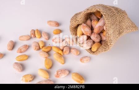 Peanuts in jute sack bag, white ground roasted peanuts poured. Stock Photo