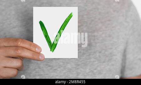 Man holding an approval sign. Green checkmark sign. OK. Okay. OK. The male. Stock Photo