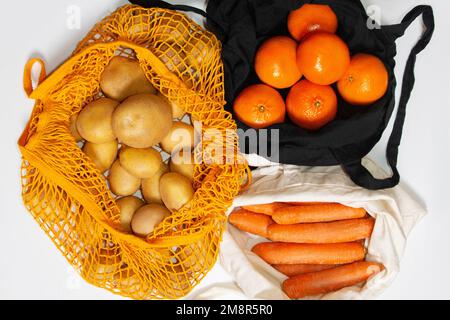 Fresh farm vegetables and fruits. Reusable shopping bags. Fabric bag, mesh bag, string bag. Filled with vegetables and fruits. Potatoes, carrots, tang Stock Photo