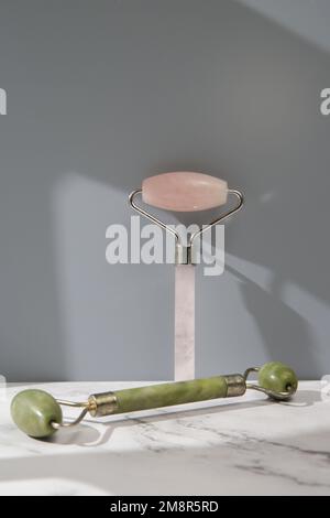 Rose quartz and jade facial roller for anti aging facial massage. Skin care luxury beauty tools. Stock Photo