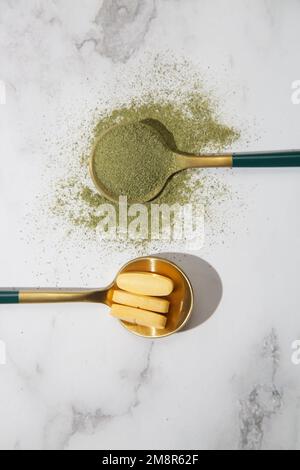 Green powder and pills in spoons. Concept of nutritional supplement, dieting, detox, preventive healthcare and healthy lifestyle. Stock Photo