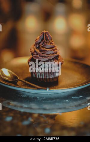 Chocolate cupcake with cacao cream on coffee shop marble counter. Stock Photo