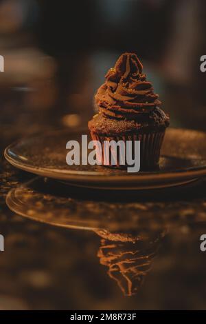 Chocolate cupcake with cacao cream on coffee shop marble counter. Stock Photo